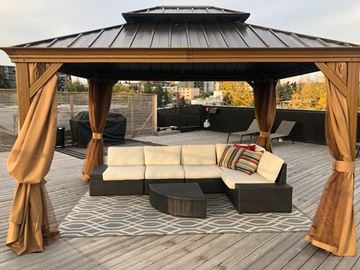 Calgary apartment for rent - A wooden gazebo with a white couch and a black table in front of it.