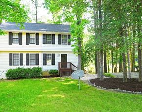 Raleigh house for rent - A white house with a green lawn and trees in the background.