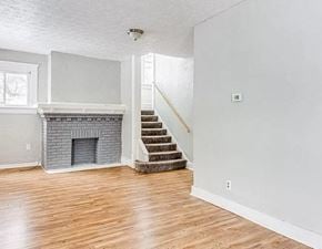Akron apartment for rent - an empty living room with a brick fireplace and wooden floors