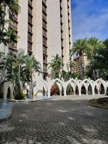 Honolulu apartment for rent - a courtyard with palm trees in front of a tall building