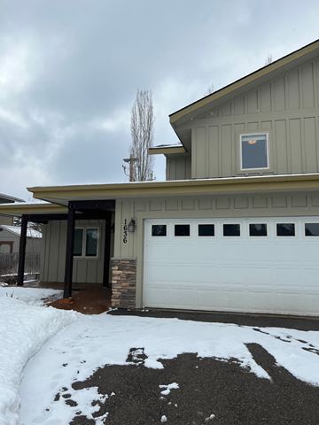 Whitefish apartment for rent - A house with a garage and a driveway covered in snow.