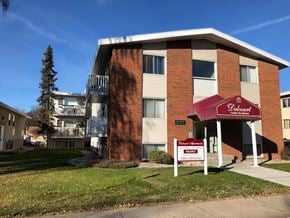 Edmonton apartment for rent - A red and white sign in front of a brick building advertises a sale.