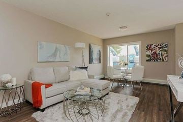 Edmonton apartment for rent - A living room with a white couch, glass coffee table, and a painting on the wall.