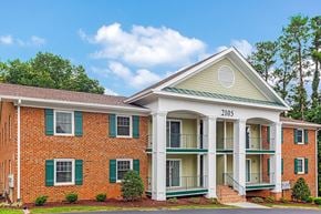 Raleigh apartment for rent - A red brick building with green shutters and a white porch.