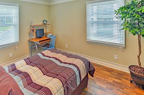 Raleigh apartment for rent - A bedroom with a bed, desk, chair, and a potted plant.