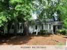 Raleigh house for rent - a house surrounded by trees with a dirt driveway