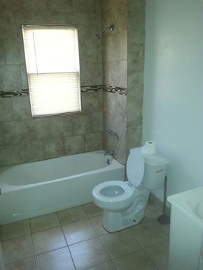 Detroit apartment for rent - A white toilet sits next to a bathtub in a bathroom.