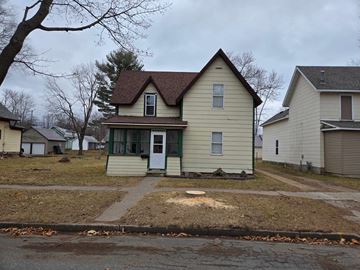 Menomonie house for rent - a yellow house with a yard in front of it