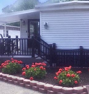 Green apartment for rent - a house with a deck and flowers in front of it