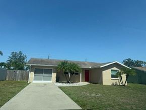 Sarasota house for rent - A house with a red door and a tree in front.