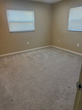 Sarasota house for rent - A room with a carpeted floor and two windows.