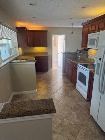 Sarasota house for rent - A kitchen with a white refrigerator and brown cabinets.