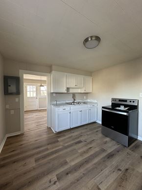 Hopkinsville house for rent - an empty kitchen with white cabinets and a stove and a sink