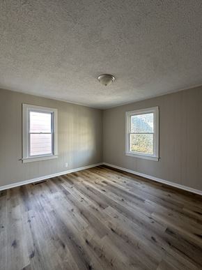 Hopkinsville house for rent - an empty living room with wooden floors and two windows
