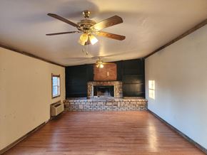 Jones house for rent - an empty living room with a ceiling fan and a fireplace