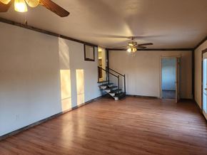 Jones house for rent - an empty living room with wooden floors and a ceiling fan