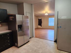 Jones house for rent - an empty kitchen with a refrigerator and a hard wood floor