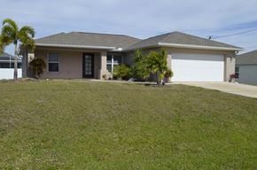 Cape Coral house for rent - a house with a lawn and palm trees in front of it