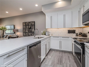 Waukee apartment for rent - A modern kitchen with white cabinets and a wooden floor.