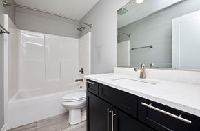 Waukee apartment for rent - A white toilet sits in a bathroom with a black vanity.