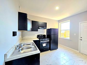 Chicago apartment for rent - A kitchen with black appliances and a marble floor.