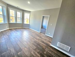 Chicago apartment for rent - A room with wooden flooring and a door leading to another room.