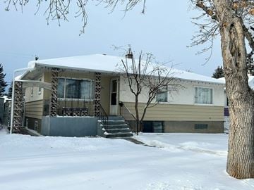 Calgary apartment for rent - A house with a snow-covered roof and a tree in front.
