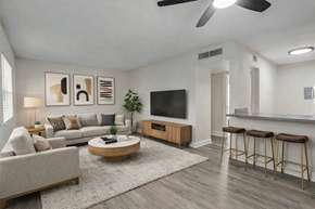 Tampa apartment for rent - A living room with a grey couch, a coffee table, a television, and a bar area.