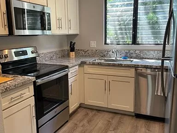 Kihei apartment for rent - a kitchen with stainless steel appliances and white cabinets