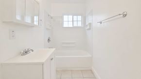 Anaheim apartment for rent - A white bathroom with a sink, mirror, and bathtub.