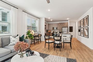 Charlotte apartment for rent - A modern living room with a grey sofa, a coffee table, and a dining table set up with chairs.