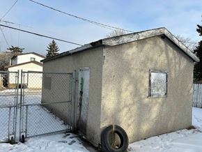 Prince Albert house for rent - A small concrete building with a tire leaning against it in the snow.
