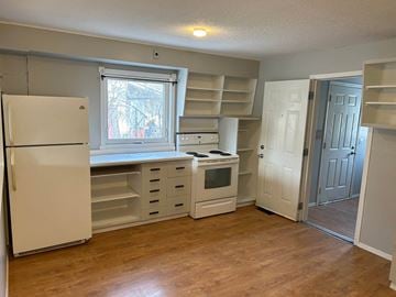 Prince Albert house for rent - A kitchen with a white refrigerator, a window, and a white oven.