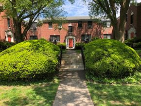 Swarthmore apartment for rent - A red brick building with a red door and two green bushes on either side.