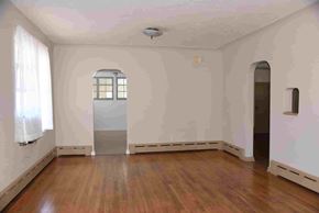 Trinidad house for rent - an empty living room with wood floors and white walls