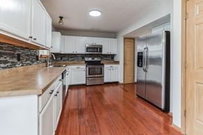 Louisville house for rent - a kitchen with white cabinets and a stainless steel refrigerator