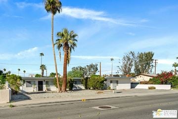 Palm Springs apartment for rent - an empty street in front of a house with palm trees