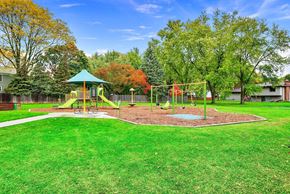 Geneva apartment for rent - A playground with a green swing set and a red slide.