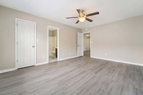 Jacksonville house for rent - A spacious room with a ceiling fan and light, hardwood floors, and white walls.