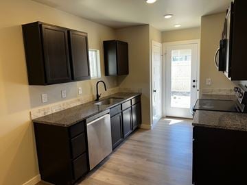 Odessa house for rent - A kitchen with black cabinets and a granite countertop.