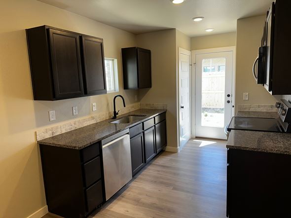 Odessa house for rent - A kitchen with black cabinets and a granite countertop.