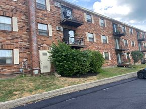Milford apartment for rent - A brick building with a balcony and a car parked in front.