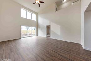 Tinley Park house for rent - an empty living room with white walls and a ceiling fan