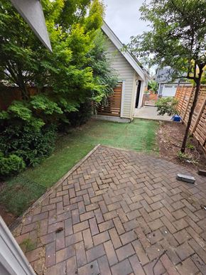 New Westminster apartment for rent - A backyard with a brick walkway and a small house.