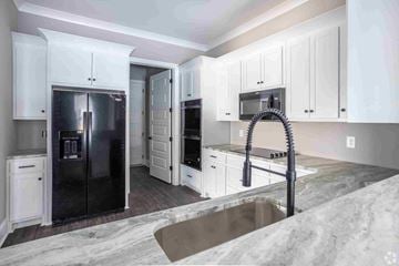 Columbus apartment for rent - A kitchen with white cabinets and a black fridge.