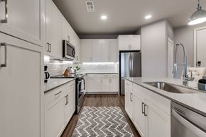 Mckinney house for rent - an open kitchen with white cabinets and stainless steel appliances