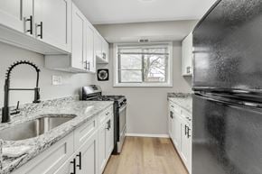 Capitol Heights apartment for rent - a kitchen with white cabinets and a black refrigerator