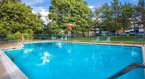 Suitland apartment for rent - A swimming pool surrounded by trees and a fence.
