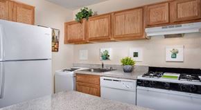 Suitland apartment for rent - A kitchen with a white refrigerator, a white dishwasher, and a black stove top oven.