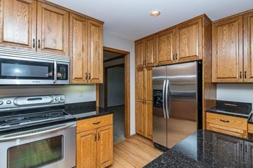 Rochester house for rent - A kitchen with wooden cabinets and a black countertop.